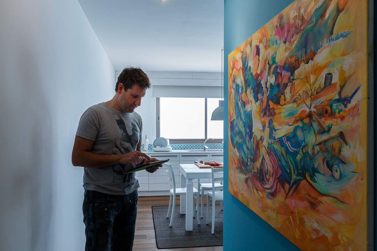 open space in legno bianco e pavimento in rovere ricco di quadri e arte tropicale