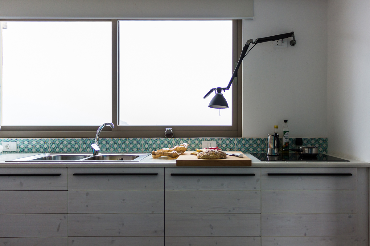 cucina in legno bianco e ceramica decorata con vista sull'oceano